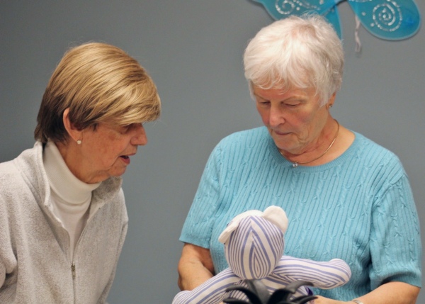 Volunteer Pat Krolick holds a Memory Bear as she talks to another woman