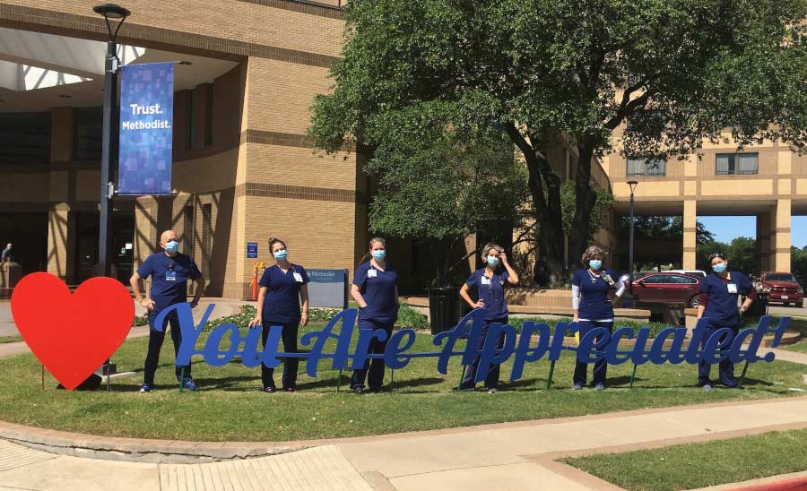 Methodist Dallas Medical Center employees stand with signs that spell out You Are Appreciated