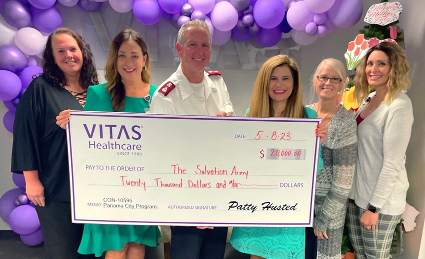 A group of people stands around an oversized novelty check.