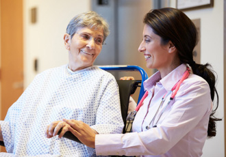 A physician talks with a patient who is resting in a wheelchair